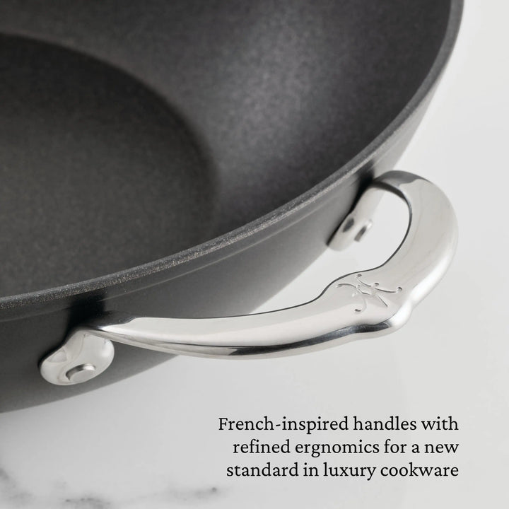 Close-up of the black TITUM® Fusion TITUM Nonstick Stock Pot with Lid, 8-Quart, featuring a curved, engraved metal handle. Image text: French-inspired ergonomic handles define luxury in nonstick cookware.