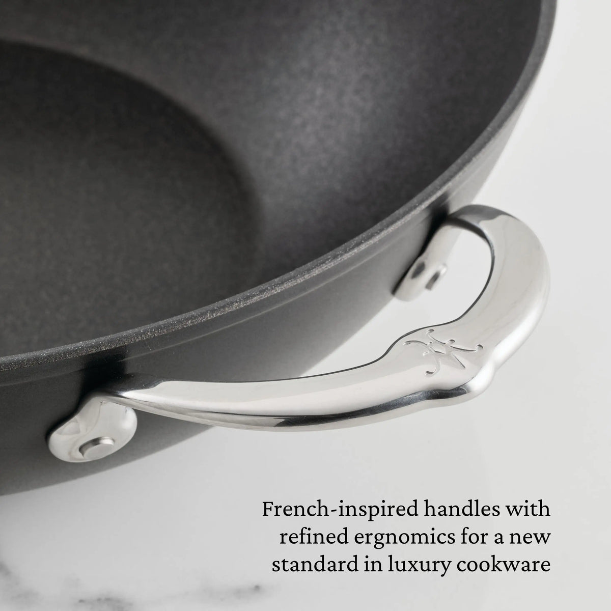 Close-up of the black TITUM® Fusion TITUM Nonstick Stock Pot with Lid, 8-Quart, featuring a curved, engraved metal handle. Image text: French-inspired ergonomic handles define luxury in nonstick cookware.