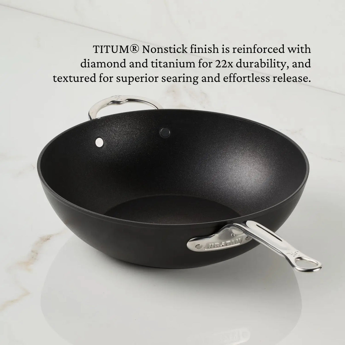 A 12.5-inch TITUM® Fusion TITUM Nonstick Wok with stick handle and dome lid rests on a white countertop, showcasing its durable, textured TITUM® Nonstick finish and Italian craftsmanship.