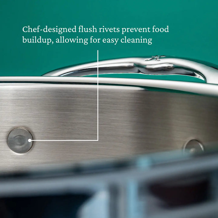 Close-up of the ProBond Professional Clad Stainless Steel Sauteuse with Lid, 3.5-Quart, handcrafted in Italy against a green background. A labeled arrow points to the chef-designed flush rivets, annotating them as preventing food buildup for easy cleaning.