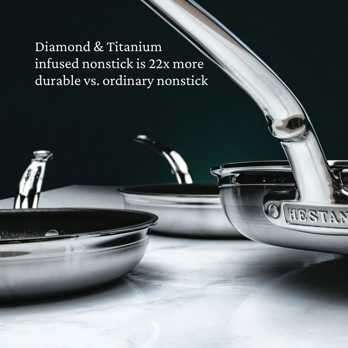 Three ProBond® Forged™ Professional Clad Stainless Steel TITUM® Nonstick Skillets with shiny handles sit on a white surface. Text reads: “Diamond & Titanium infused TITUM Nonstick is 22x more durable vs. ordinary nonstick.”.