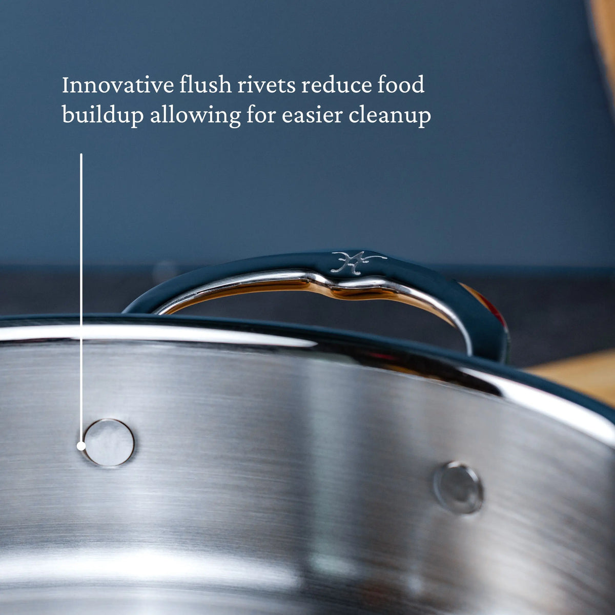 Close-up of a CopperBond Copper Induction Set, 24-Piece stainless steel pot features flush rivets and a shiny handle. Text: “Innovative flush rivets reduce food buildup for easier cleanup.” Handcrafted in Italy.