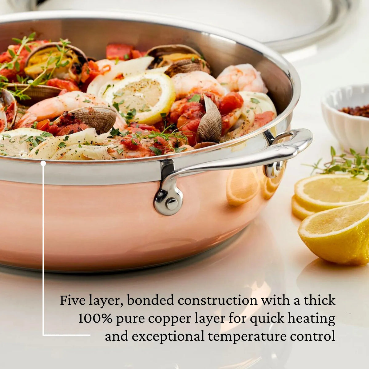 A Copper Induction Dutch Oven, 5-Quart by CopperBond is filled with a seafood dish of shrimp and clams, garnished with lemon slices and herbs. The text highlights the pots five-layer bonded design featuring a pure copper layer for even cooking.