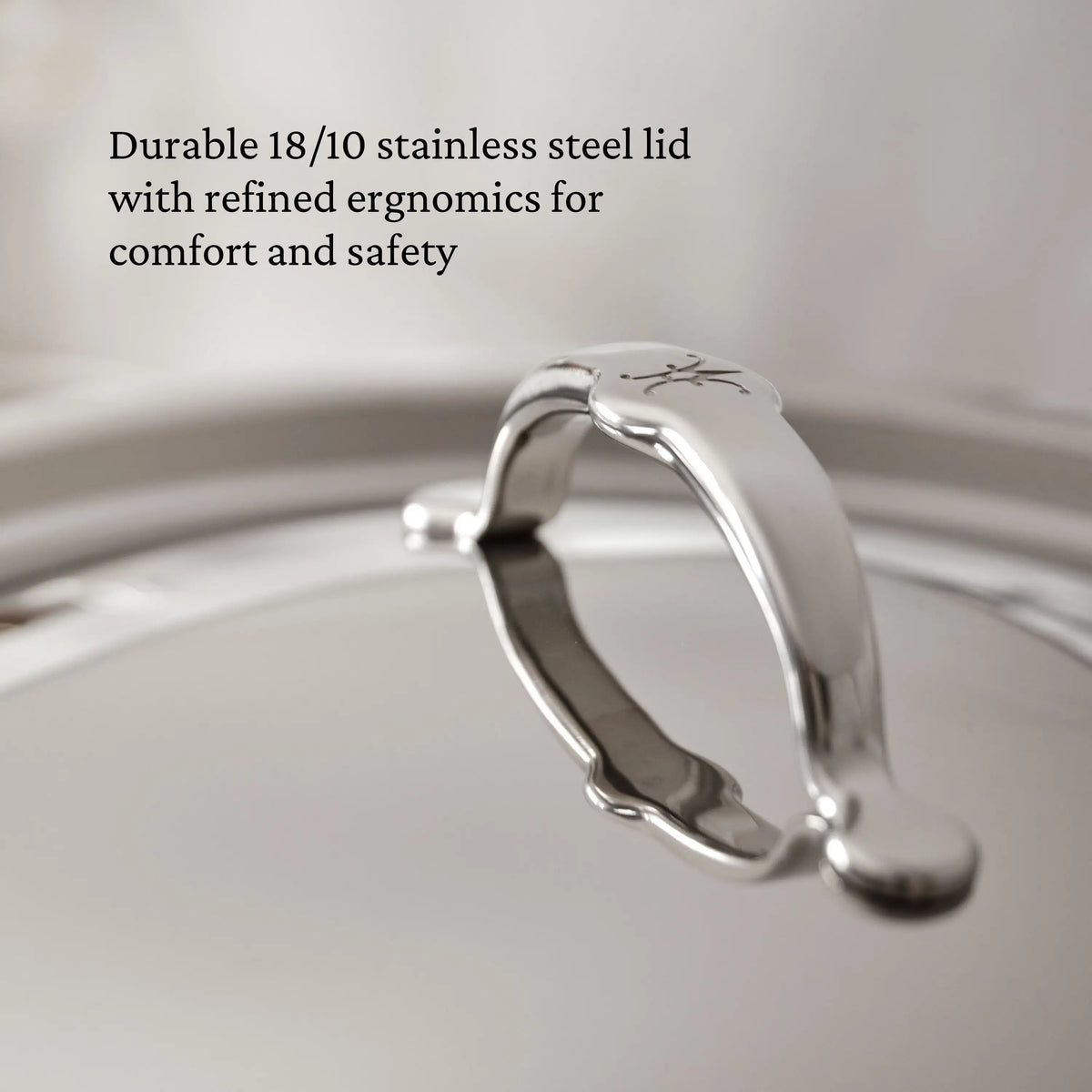 Close-up of a ProBond® Luxe™ Polished Clad Stainless Steel Saucepans lid, featuring a curved handle. Text highlights its durable 18/10 stainless steel construction and ergonomic design for comfort and safety.