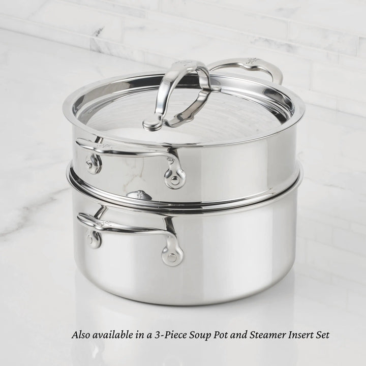 A ProBond® Luxe™ Professional Clad Stainless Steel Soup Pot with Lid sits on a matching steamer insert, both with metal handles, on a white marble countertop. Also available as a 3-piece Soup Pot and Steamer Insert Set.