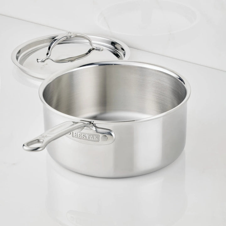 A ProBond® Luxe™ Polished Clad Stainless Steel Saucepan with Lid sits on a white surface. The lid is slightly open, showing the shiny interior and handle, while the premium cookware’s brand name is visible on its side.