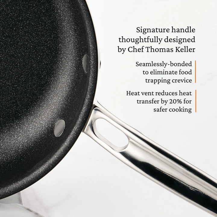 Close-up of a black Polished Clad Stainless Steel Skillet with TITUM® Nonstick from ProBond® Luxe™, featuring Chef Thomas Keller’s handle design, seamless bonding to prevent food traps, and a vent that cuts heat transfer by 20%.