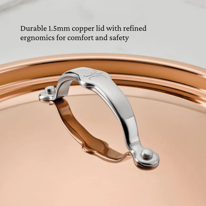 A close-up of a copper pot lid with a silver metal handle, showcasing the handle’s ergonomic contours. Text above reads: Durable 1.5mm copper lid with refined ergonomics for comfort and safety—an essential piece from the CopperBond® Aura™ Polished Copper 10-Piece Cookware Set or any premium copper cookware collection.