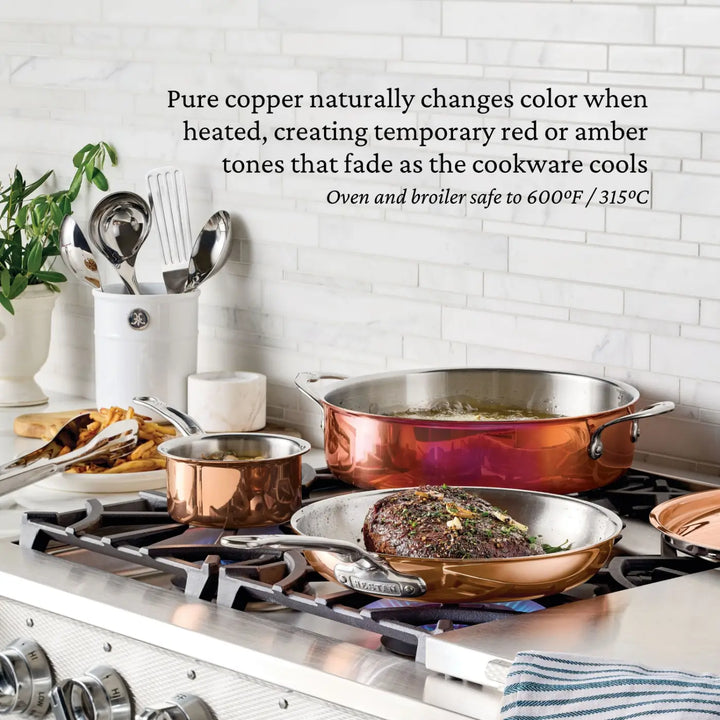 Here’s a rewritten version using your product data: CopperBond® Aura™ Polished Copper 10-Piece Cookware Set rests on the stove: a steak sizzles in a frying pan, broth simmers in the saucepan, and the Dutch oven is covered. Utensils are stored neatly in a holder beside a plant on the counter. The display details how CopperBond® Aura™ copper cookware changes color with heat.