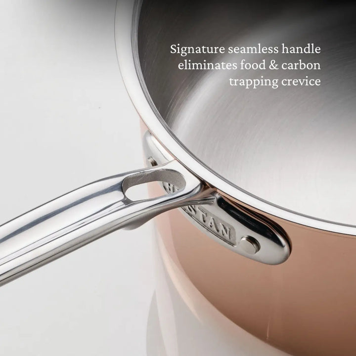 A close-up of a saucepan from the CopperBond® Aura™ Polished Copper 10-Piece Cookware Set highlights a seamless metal handle integrated with its copper body. Text notes that this handle design eliminates any crevices where food or carbon could become trapped.