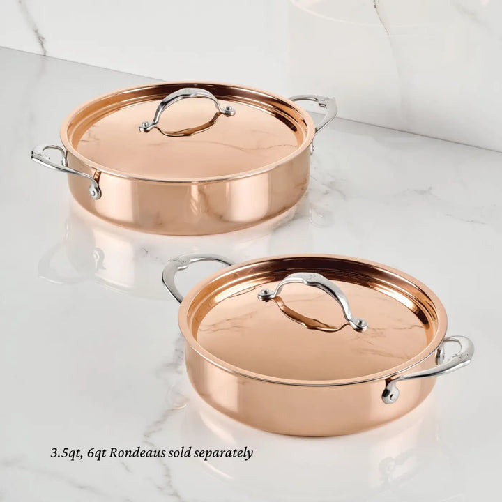Two CopperBond Aura™ Polished Copper Rondeaus with lids, each featuring two silver handles, are displayed on a white marble surface. The image shows the 3.5-quart and 6-quart professional-grade rondeau pots, which are sold separately.