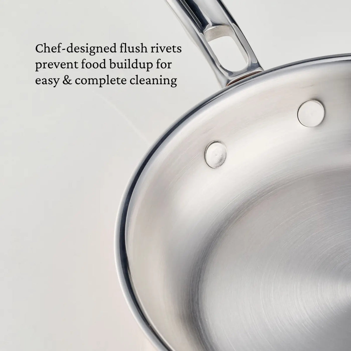 A close-up of a stainless steel pan with flush rivets on the interior, accompanied by text describing how the rivets prevent food buildup for easier cleaning—just like the innovative design found in CopperBond Aura™ Polished Copper Skillets.