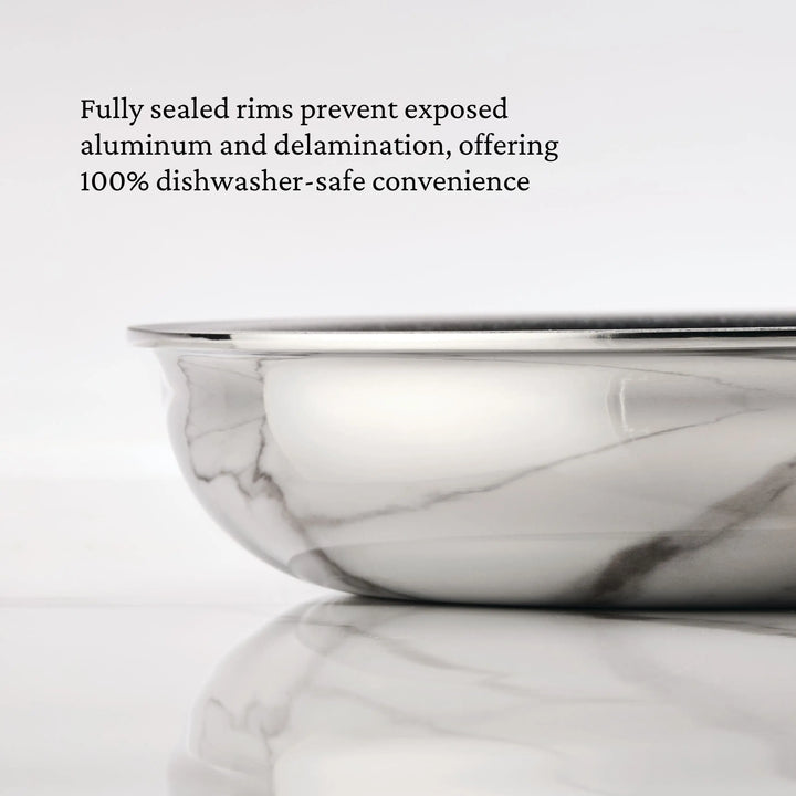 A close-up of the ProBond® Luxe™ Polished Clad Stainless Steel Signature Set, 7-Piece, shows its shiny sealed rim on marble, highlighting how this tri-ply clad cookware stays durable and dishwasher-safe by preventing exposed aluminum.