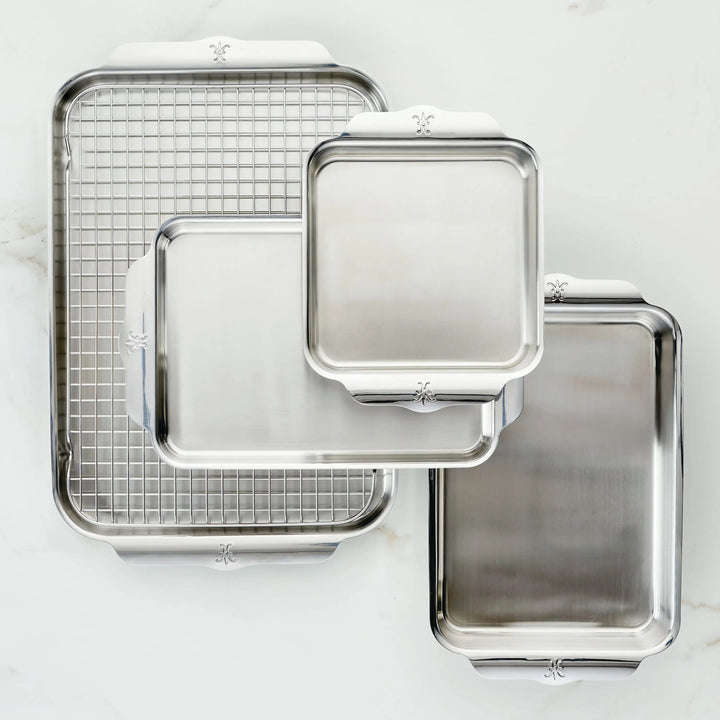 The Hestan OvenBond Tri-ply 5-Piece Set, made of stainless steel, includes varying-sized oven safe pans—one with a metal cooling rack. All pieces feature rounded edges and flat handles for durability and convenience.