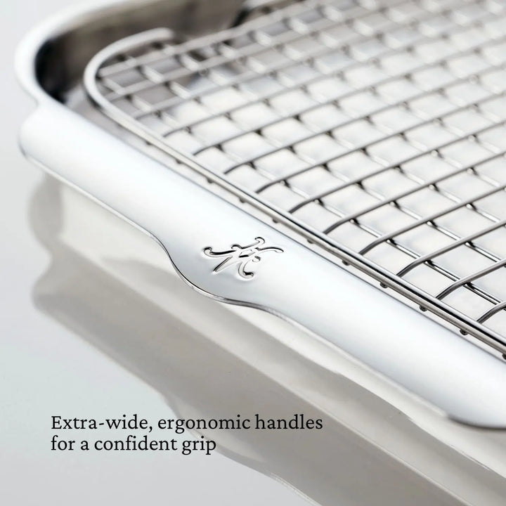 Close-up of a Hestan OvenBond Tri-ply 5-Piece Set cooling rack featuring extra-wide, ergonomic handles engraved with a decorative letter. Text reads: Extra-wide, ergonomic handles for a confident grip.