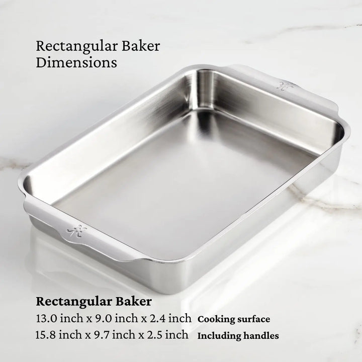 A Hestan OvenBond Tri-ply 5-Piece Set bakeware pan is shown on a marble surface. Dimensions are listed as 13 x 9 x 2.4 inches for the cooking area and 15.8 x 9.7 x 2.5 inches with handles.