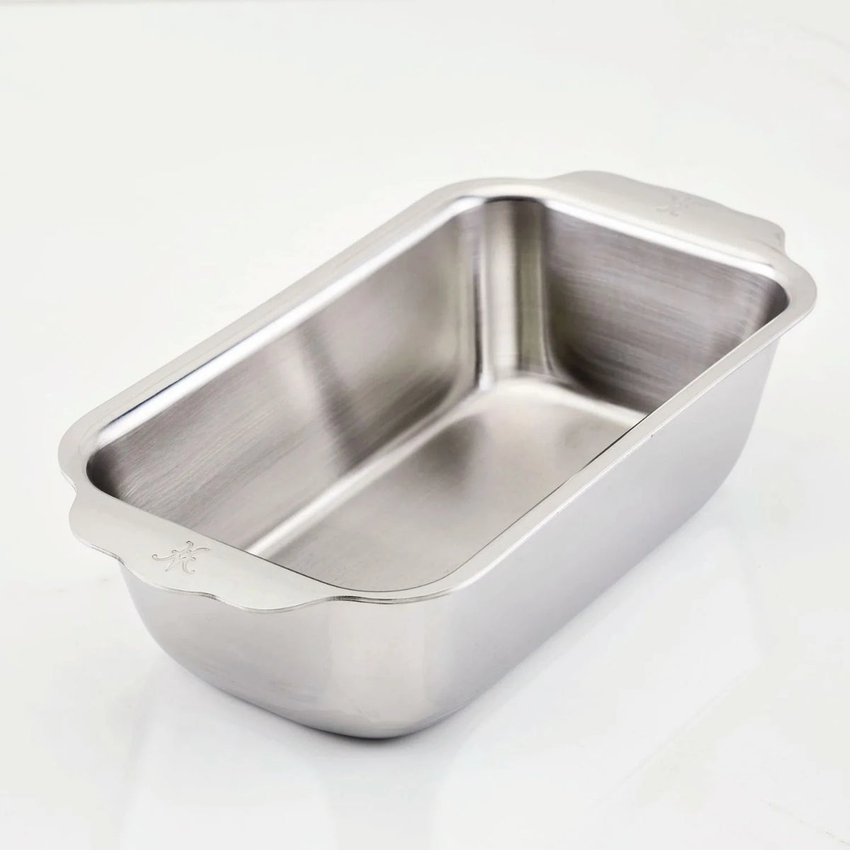 The Hestan OvenBond Tri-ply Stainless Steel 1-Pound Loaf Pan, featuring rounded corners and two small handles, is shown on a plain white surface.