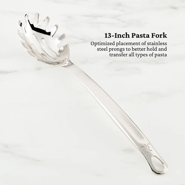 A 13-inch stainless steel pasta fork from the Hestan Provisions Deluxe Chefs Tool Set is displayed on marble. Its design, perfect for transferring pasta, features finely optimized prongs for performance and is highlighted as essential among chefs tools.