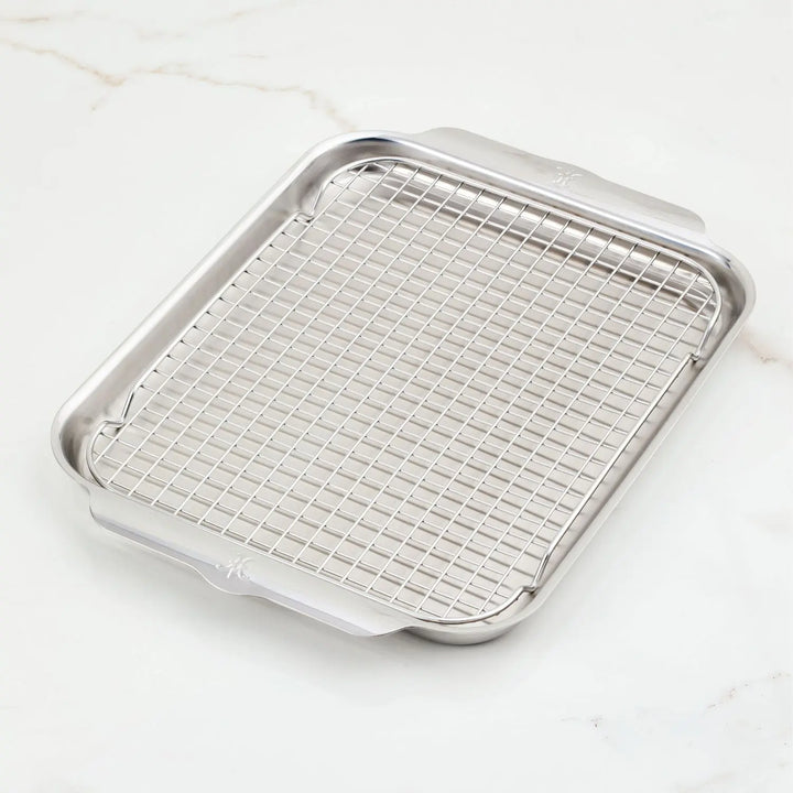 A Hestan OvenBond Tri-Ply Medium Sheet Pan & Rack, 12-in x 15-in, rests on a white marble surface.