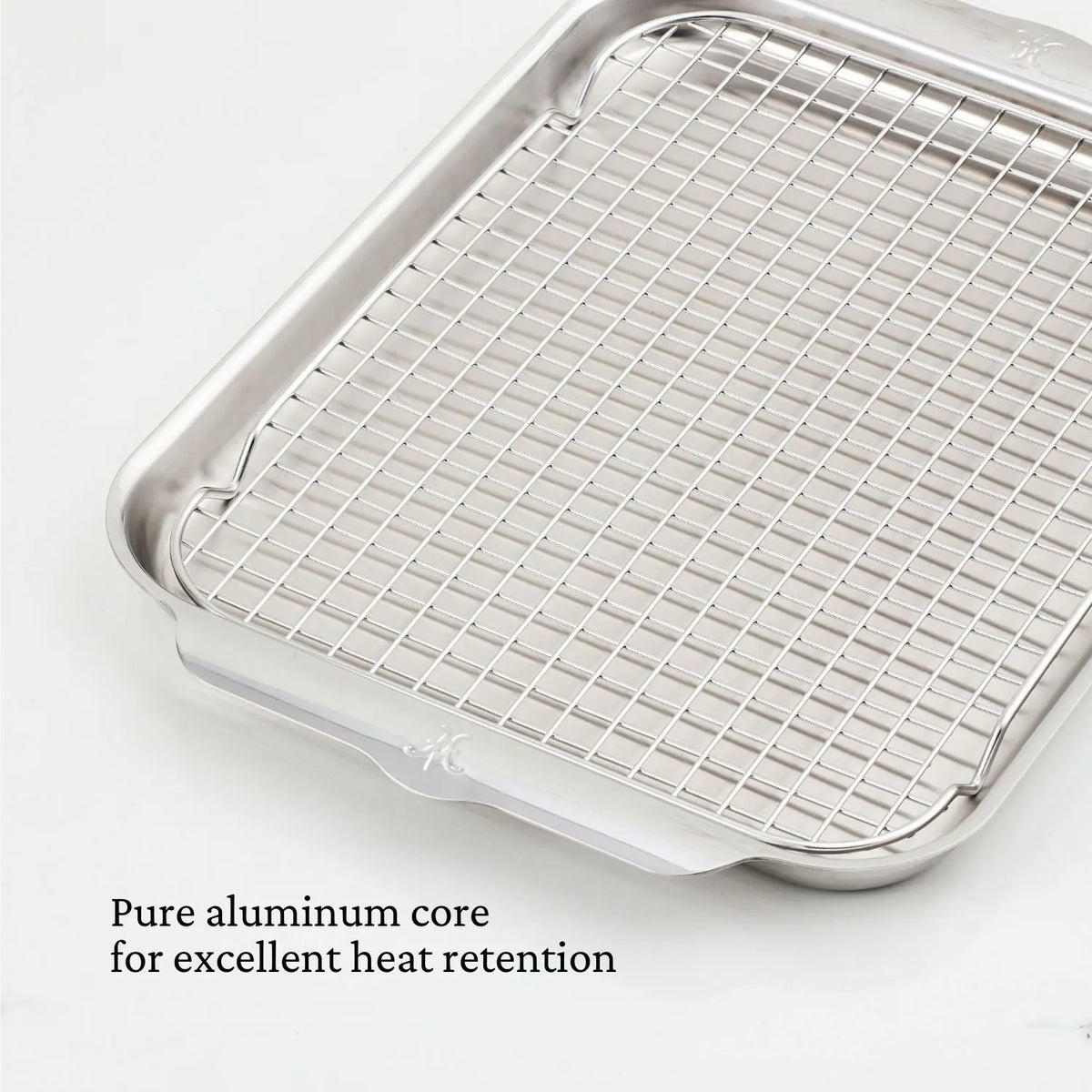 A Hestan OvenBond OvenBond Tri-Ply Medium Sheet Pan & Rack (12"x15") is shown on a white background. Text in the bottom left reads: Pure aluminum core for excellent heat retention.