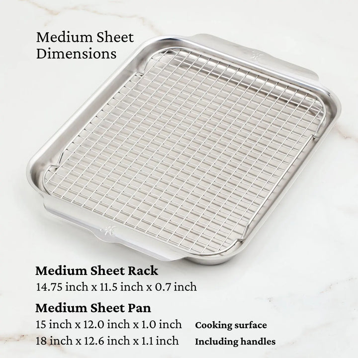 The Hestan OvenBond Tri-ply Gourmet Essentials Stainless Steel 7-piece Set includes a medium sheet pan (15 x 12 x 1 in; 18 x 12.6 x 1.1 in with handles) and a removable wire rack (14.75 x 11.5 x 0.7 in) displayed on marble.