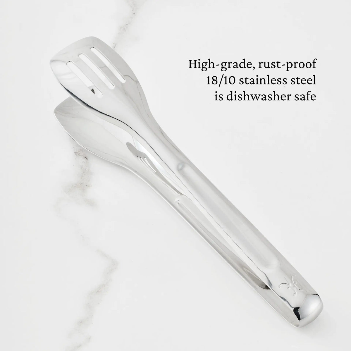 The Hestan Provisions® 10-inch Stainless Steel Serving Tongs rest on a white marble surface. Text on the image reads: High-grade, rust-proof 18/10 stainless steel is dishwasher safe.