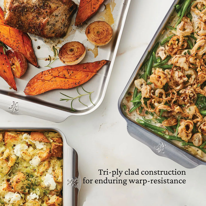 Three Hestan OvenBond pans on a white surface, each holding delicious dishes. Text: “OvenBond Tri-ply Gourmet Essentials 7-piece Set—professional-quality, warp-resistant bakeware for your kitchen.”.
