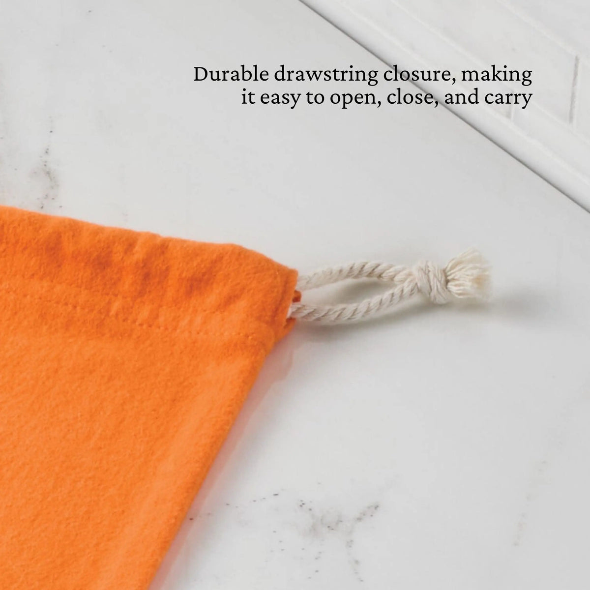 An orange Flannel Lid Storage Bag by Accessories with a white rope drawstring lies on a white surface. Text above reads: Durable drawstring closure—easy to open, close, and carry. Perfect for secure cookware storage.