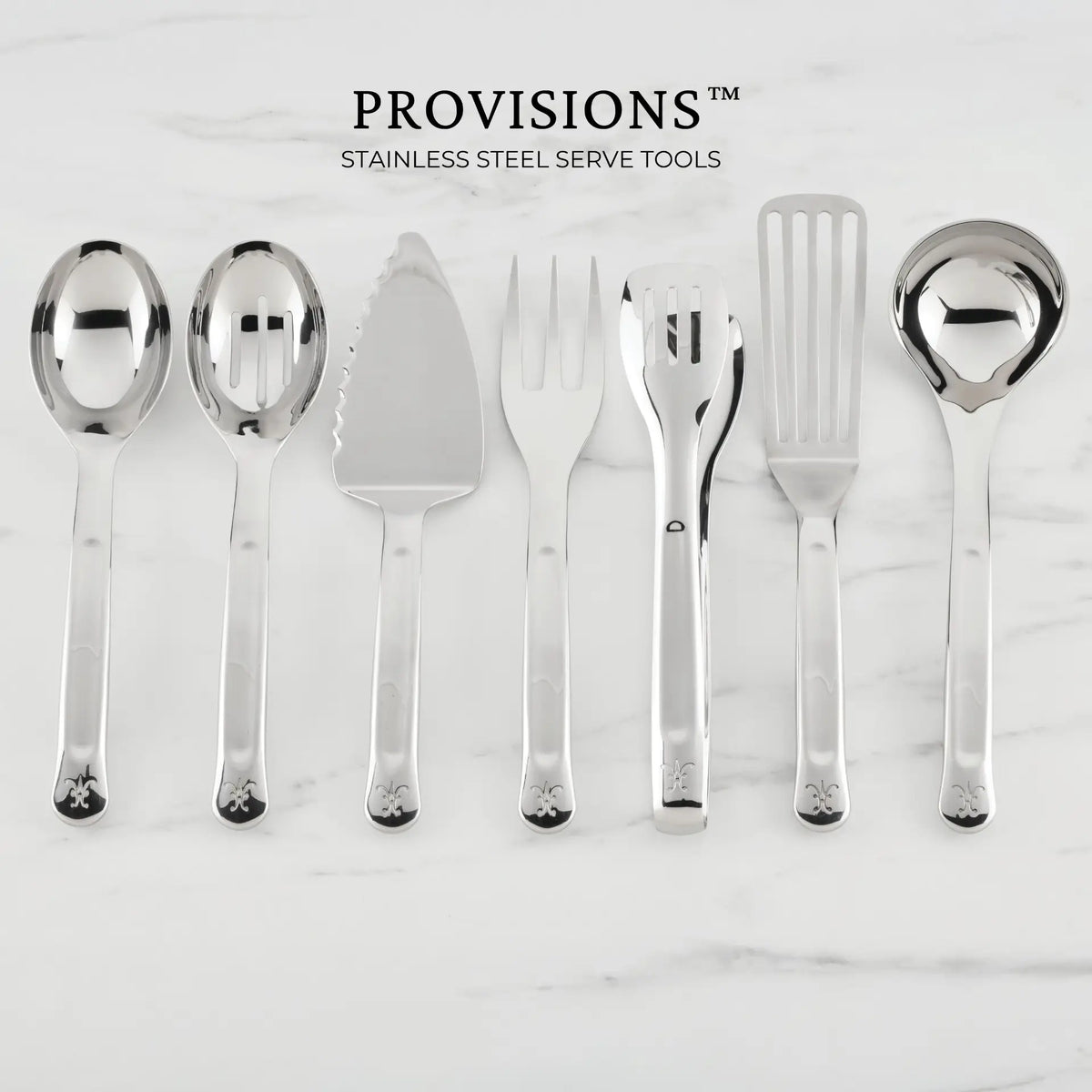 Seven Hestan Provisions® Serving Tools—including a serving spoon, slotted spoon, 10.5-inch Stainless Steel Pie & Cake Server, meat fork, salad tongs, slotted turner, and ladle—are arranged side by side on a white marble surface.
