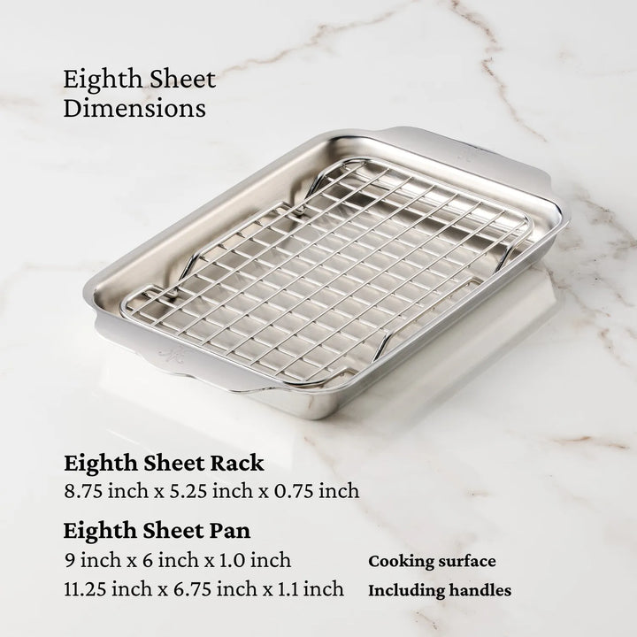 A Hestan OvenBond Tri-ply Mini Eighth Sheet Pan with Rack is displayed on a marble surface, with dimensions highlighting the measurements of the pan, rack, cooking area, and handles.