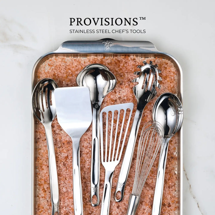 The Hestan Provisions™ Slotted Turner, 13-inch, crafted from durable 18/10 stainless steel, is pictured on pink Himalayan salt with the text above reading PROVISIONS™ Stainless Steel Chefs Tools.
