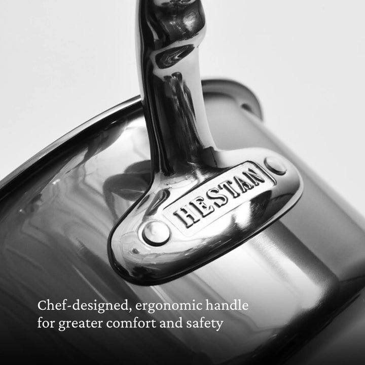 Close-up of a shiny metal handle engraved with NanoBond, highlighting the ergonomic design of the Titanium Rondeaus with Lids. Text below reads: Chef-designed, ergonomic handle for greater comfort and safety.