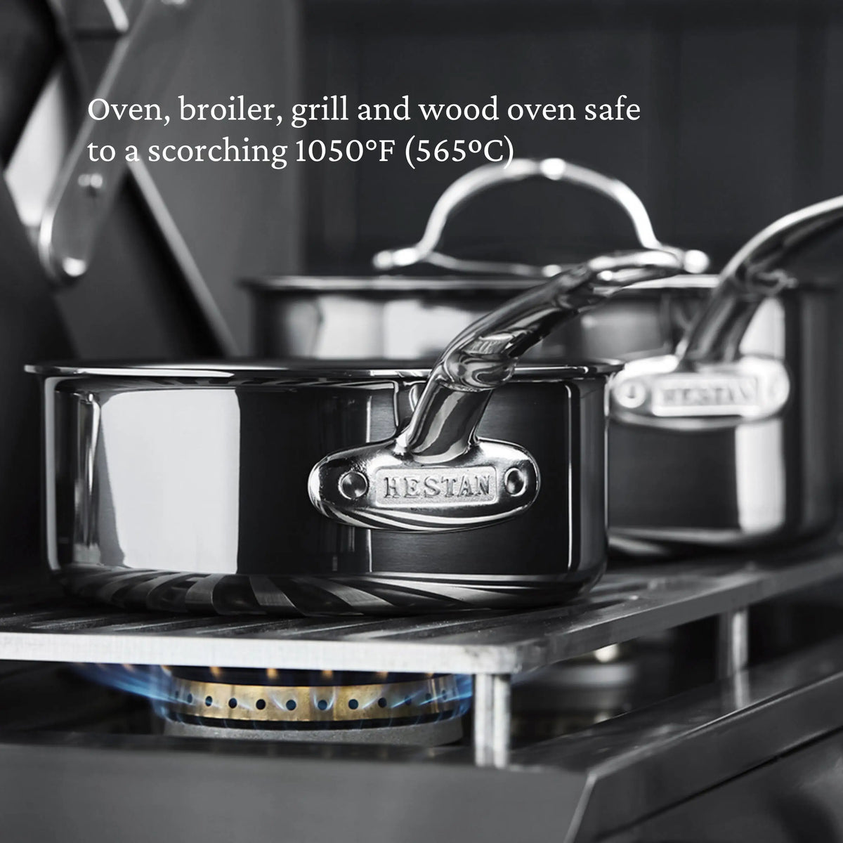 Two NanoBond Titanium Rondeaus with lids sit on a gas stove, blue flames visible. These durable pans are safe for oven, broiler, grill, and wood oven use up to 1050°F (565°C).