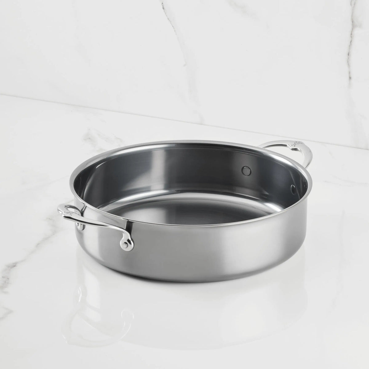 A NanoBond Titanium Rondeau with two handles and a lid rests on a white marble surface, set against a white marble background.
