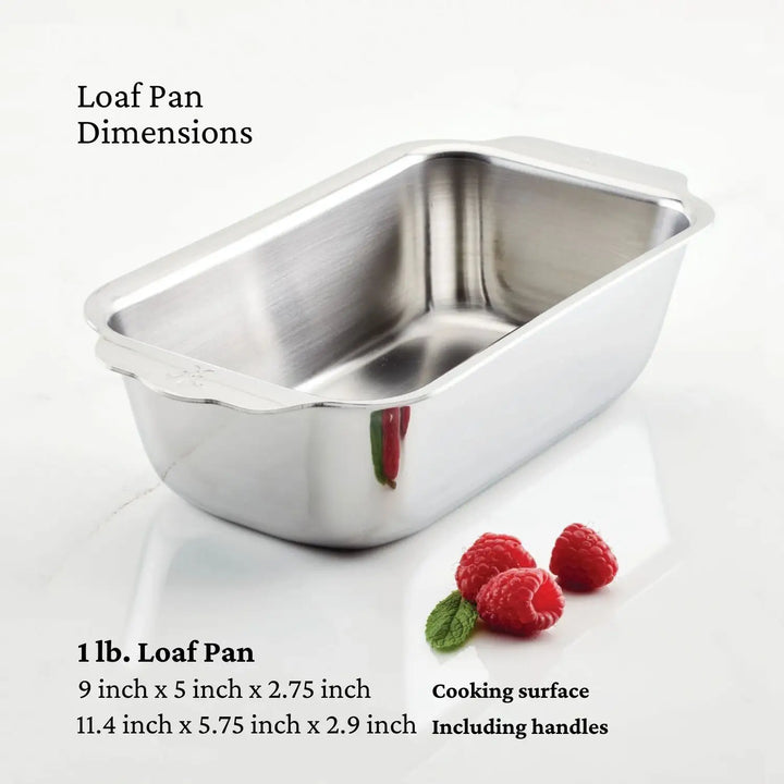 A Hestan OvenBond Tri-Ply 3-Piece Baking Set loaf pan sits on a white surface with raspberries, displaying dimensions of 9 x 5 x 2.75 in or 11.4 x 5.75 x 2.9 in including handles.