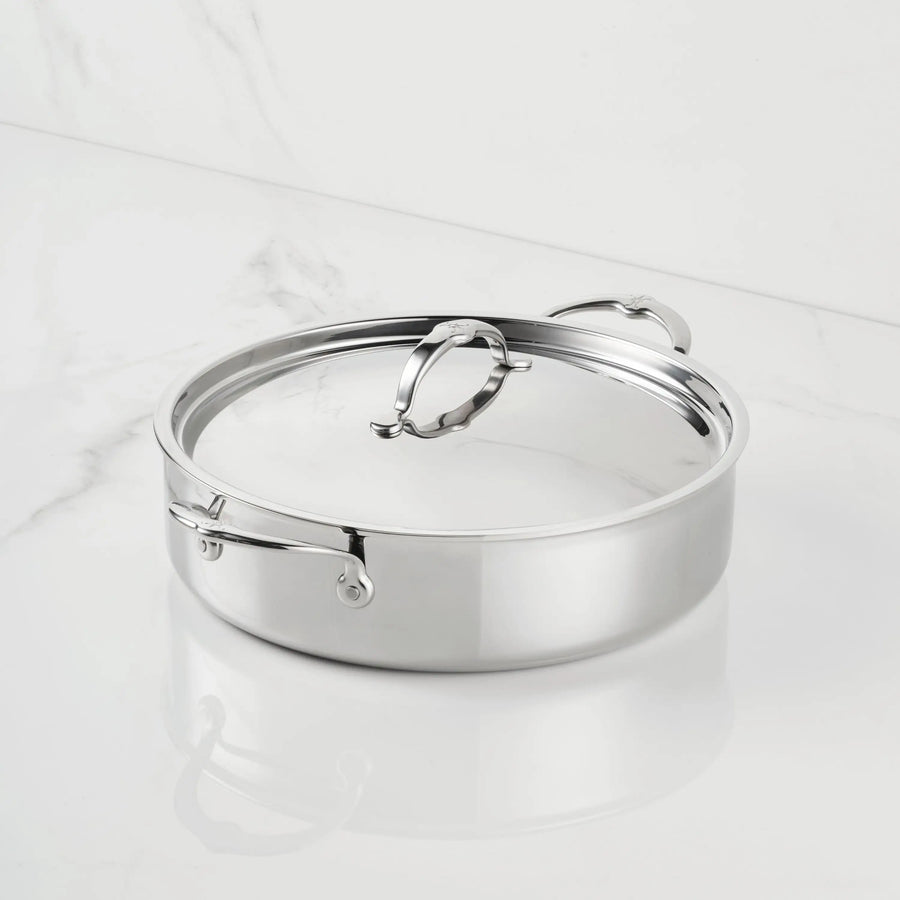 A ProBond® Luxe™ Polished Clad Stainless Steel Rondeaus with Lid, featuring two side handles and a lid handle for easy lifting, sits on a white marble surface.
