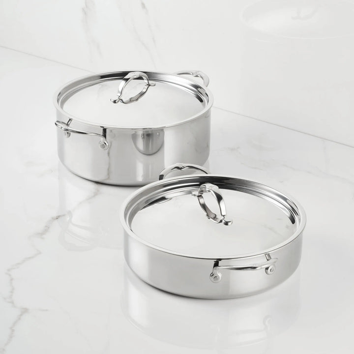 Two ProBond® Luxe™ Polished Clad Stainless Steel Rondeaus with lids sit on a white marble countertop, displaying their polished surfaces, sturdy handles, and matching metal lids that highlight premium cookware design.