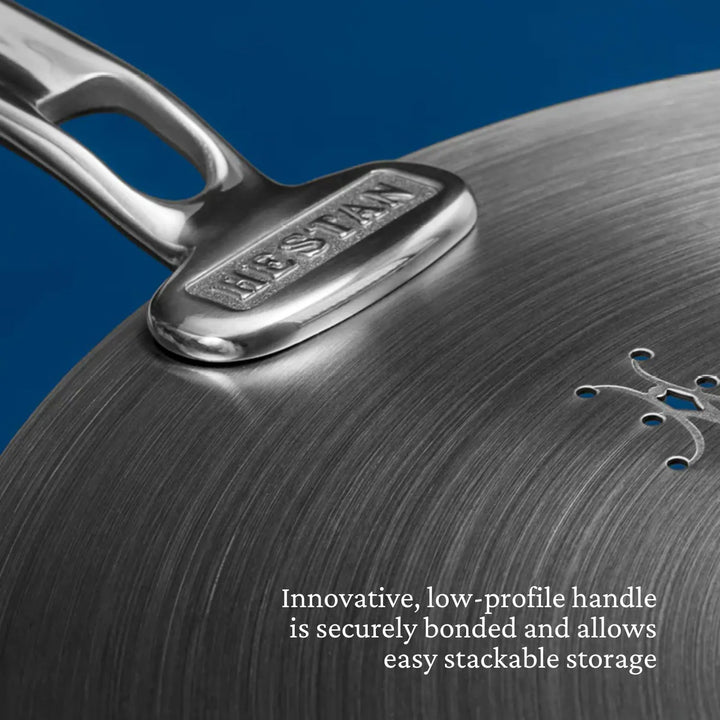 Close-up of a Thomas Keller Commercial Clad Stainless Steel 11-Piece Cookware Set pan, featuring a secure, innovative low-profile handle that's bonded for easy stackable storage in tri-ply clad cookware collections.