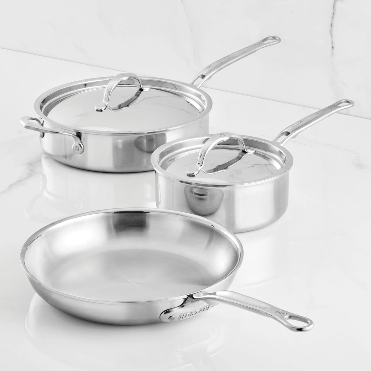 The ProBond® Luxe™ Polished Clad Stainless Steel Signature Set, 5-Piece, is displayed on a white marble surface, highlighting the quality of this professional cookware collection.